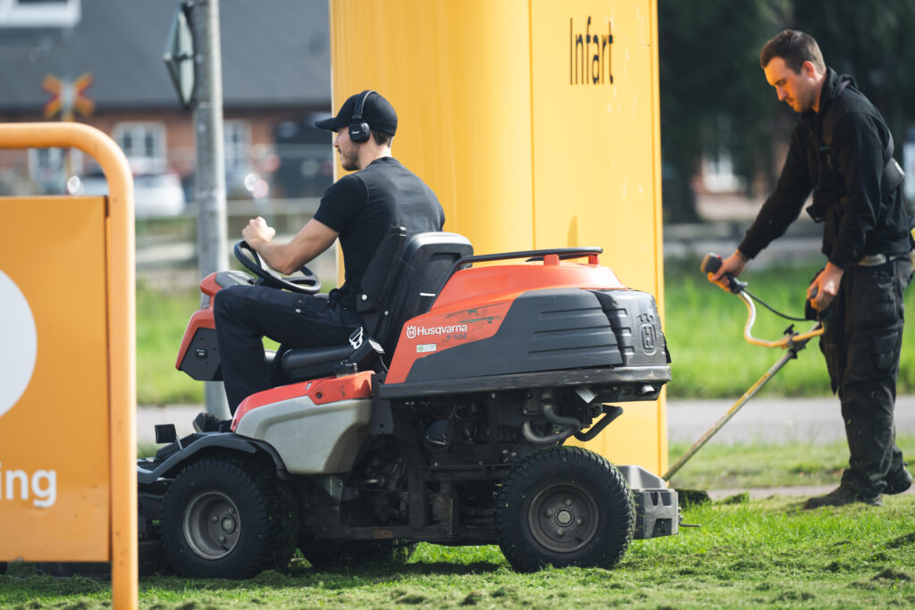 Person på gräsklippare som utför trädgårdsskötsel